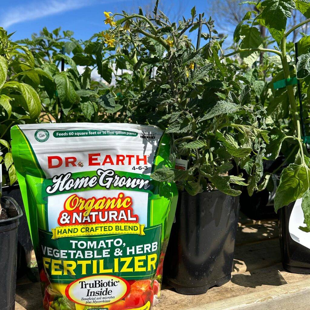 a bag of dr earth home grown organic fertilizer and plants in pots
