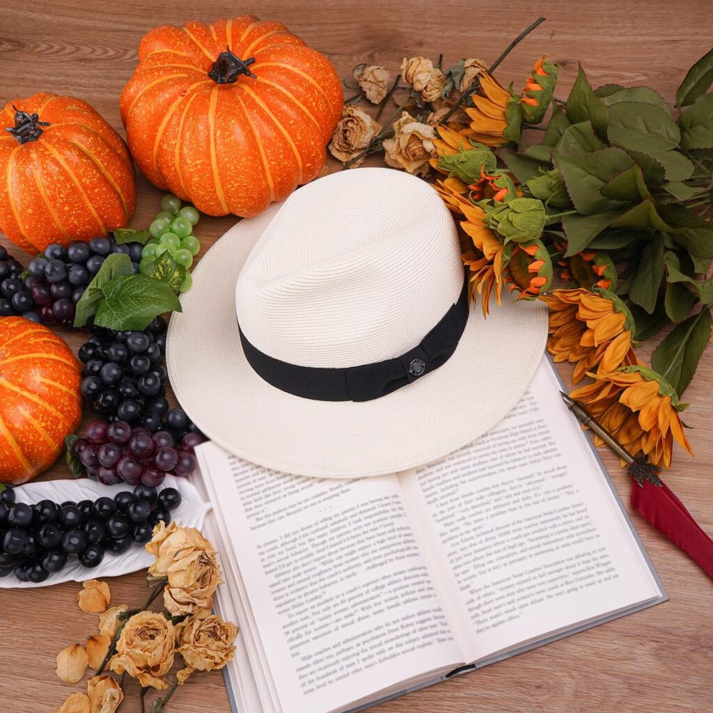 fedora hat surrounded by flowers, grapes and pumpkins