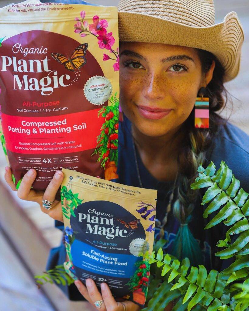 woman holding a bag of potting soil and soluble plant food by organic plant magic